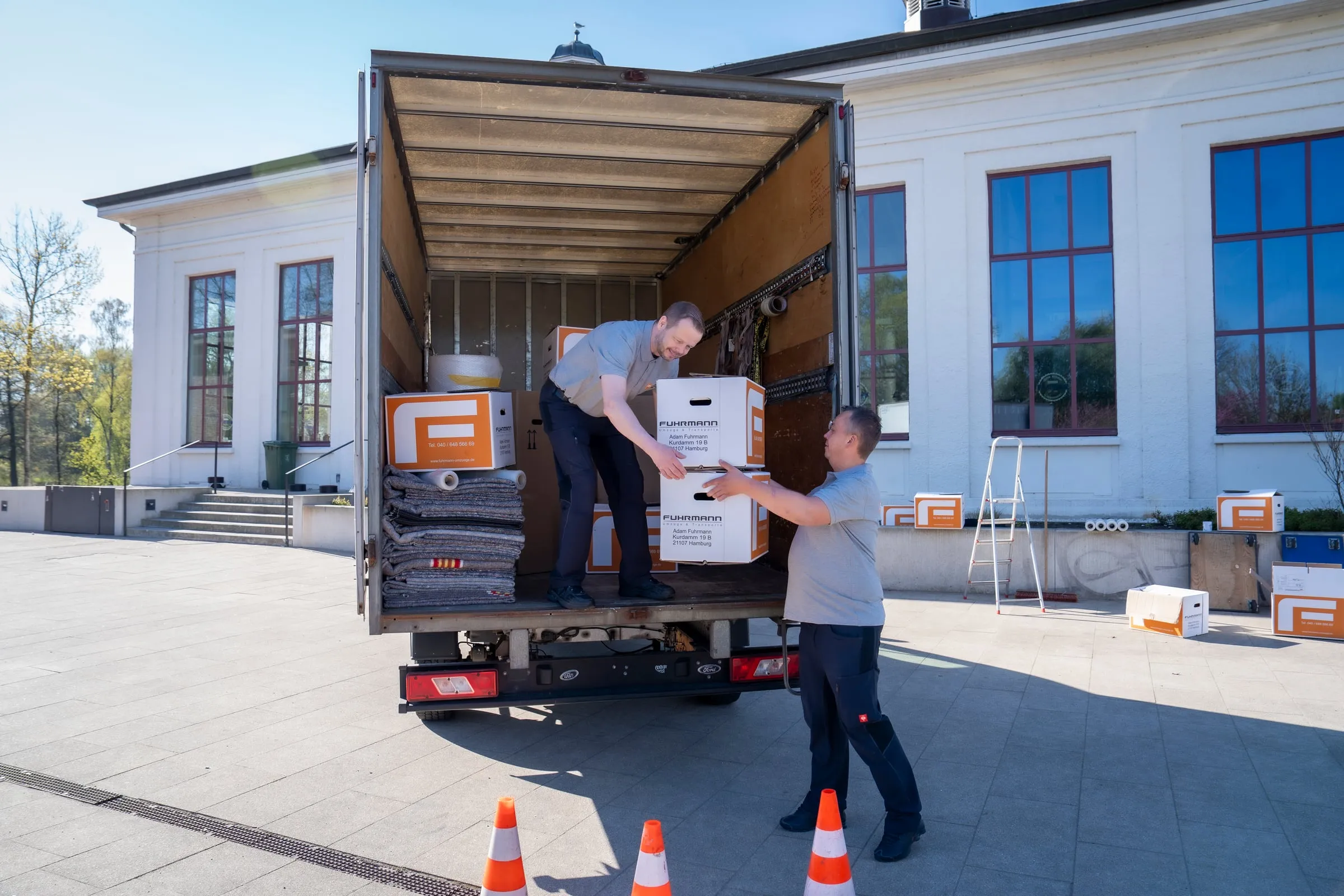 Zwei Fuhrmann-Mitarbeiter heben Umzugskartons in den LKW – Hamburger Kleinumzug