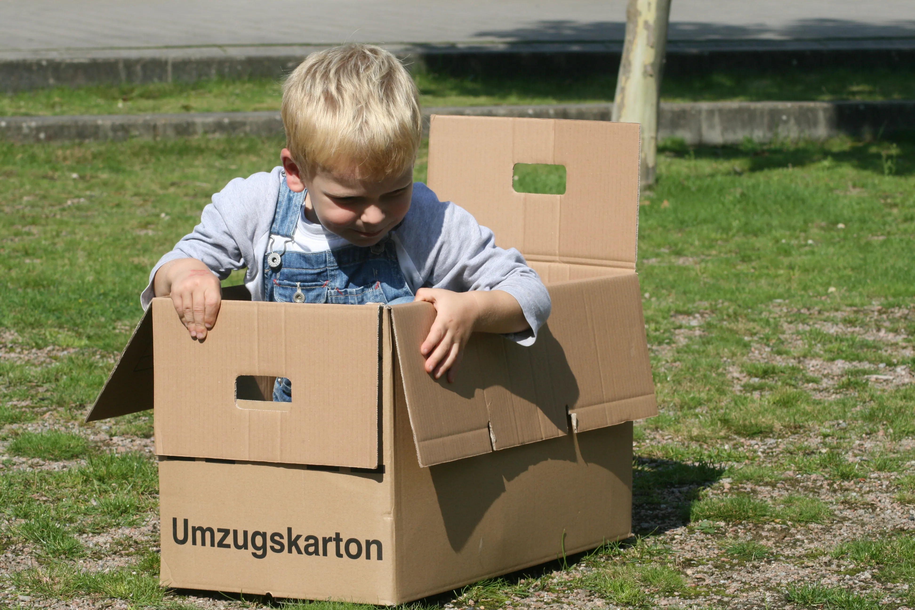 Kind spielt zwischen Umzugskartons im Freien -- Familienumzüge gehören zum Alltag in Winterhude